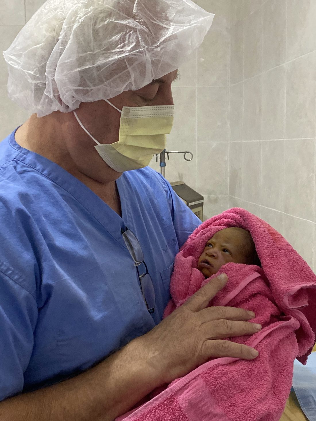 Randy Moore, registered nurse, cradling a newborn at the hospital in Cap-Haïtien