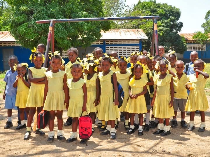 A full class of schoolchildren in yellow uniforms outside their school in Cap-Haïtien